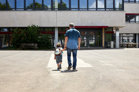 Dad takes the little boy to school or kindergarten. Parents care for their children. Start of the school year, day and lessonsの写真素材