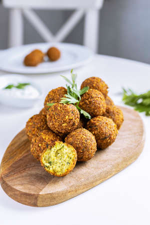 A traditional Israeli dish fresh falafel on a wooden board, garnished with a sprig of parsley....