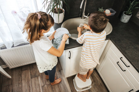 Cute Caucasian Girl And Boy Helping With Kitchen Cleaningの写真素材