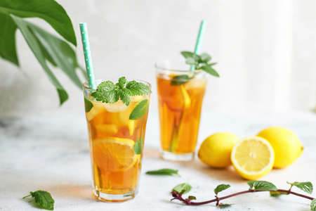 Iced iced tea in a glass with a straw, mint leaf and lemon slices inside. Cool drinks in the heatの写真素材