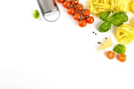 Ingredients for cooking Italian pasta on a white plate with place for text. Spaghetti, cherry tomatoes, basil, wooden spoon. Flat lay cookingの写真素材