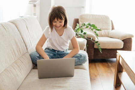 A schoolgirl girl studies at home on a laptop and makes calls with a teacher. Home education, teaching children using gadgets.の写真素材
