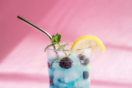 Close-up of a colorful summer blue curacao cocktail on a pink background with trendy shadows. Refreshing drinks with fresh berries. Vegan drinksの写真素材