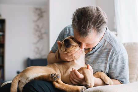 Young man hugging his labrador retriever puppy. The concept of friendship between a dog and a person, care and love for animals. Cute, funny moments of lifeの写真素材