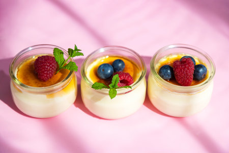 Top view of creme brulee dessert with baked sugar and fresh berries in bright sunshine on pink...