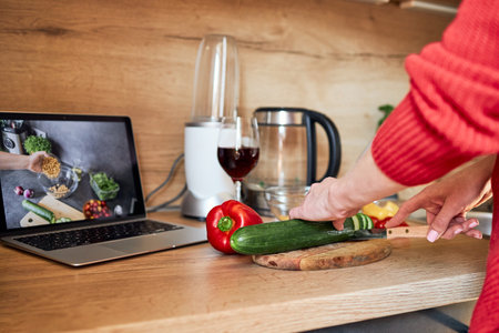 Close-up of the hands of a girl preparing a salad according to a video recipe. Cooking courses online. Video recipes and food blogの写真素材