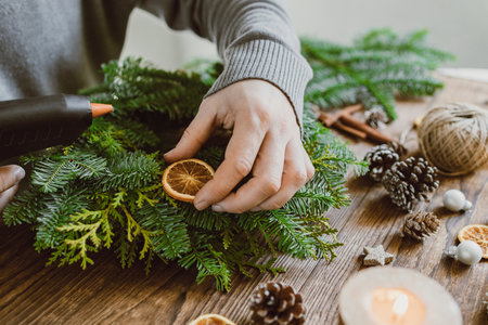 The hands of a male florist makes a New Years drenching from fresh spruce branches, cones and dried fruits. New Years master classの写真素材