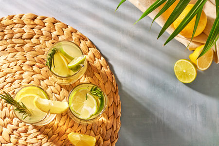 Summer refreshments, cocktails with fresh lemon, lime and rosemary in the rays of the bright sun. Cold citrus drinks on a hot dayの写真素材