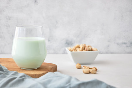 A glass of vegetable milk from nuts on the table next to pistachios. The perfect drink for vegansの写真素材