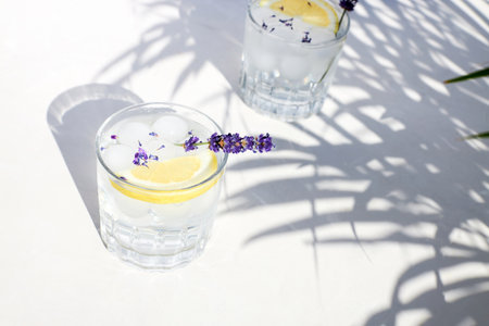 Chilled lavender lemonade with lemon and ice on a wooden stand on a gray table. Diet non-alcoholic summer cocktail. Detox water with citrusの写真素材