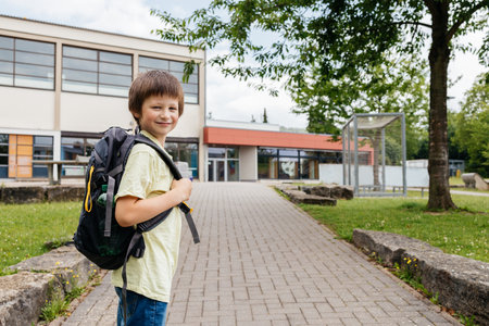 A boy with a backpack on his back walks from school. Children go to school and enjoy the beginning or end of the school year.の写真素材