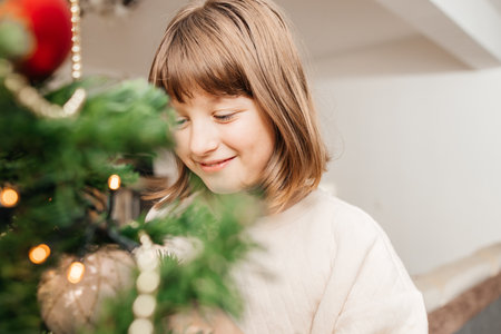 Preparing for the New Year and Christmas. Happy teenage girl decorates a Christmas tree on the eve of the holiday.の写真素材