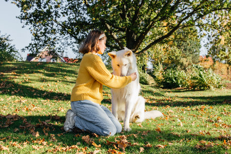 Teenage girl spending time with her dog white swiss shepherd outside. Girl playing with dogの写真素材