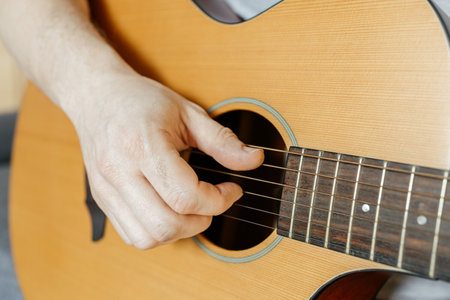 Close-up of a man's hands playing the guitar and strumming chordsの写真素材