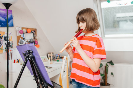 Teenage girl learning to play flute at home. Music lessons. Hobbiesの写真素材