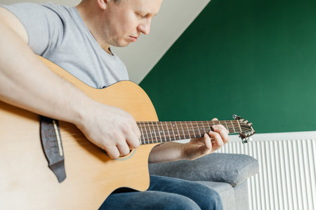 Man sitting and playing guitar, strumming chords, learning to play. Hobbies for adultsの写真素材