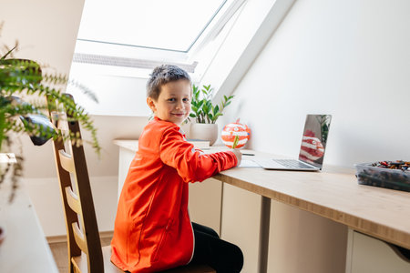 Boy learning online at home with laptop