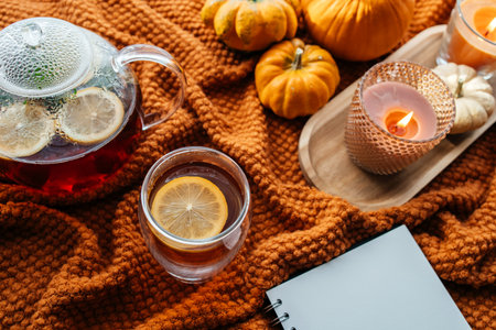 Autumn cozy mood with pumpkins, tea, and glowing candlesの写真素材