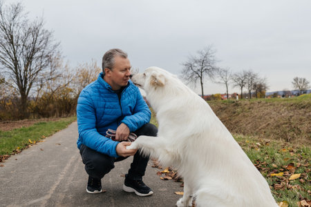 Man bonding with white shepherd dog training outdoors
