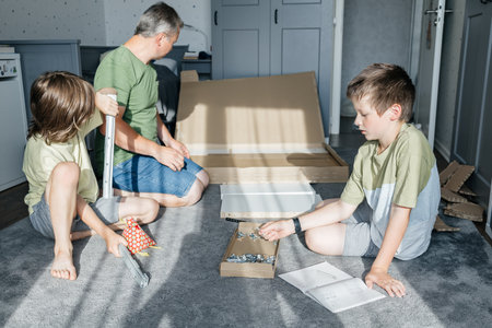Father and sons assembling furniture together at homeの写真素材