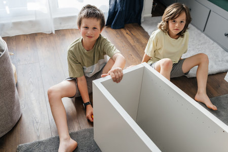 Young boys helping assemble furniture at homeの写真素材