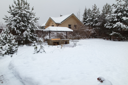 Backyard Patio.Landscape with barbeque area, snowbanks of white snow, pine trees in country garden. Country life concept.の写真素材