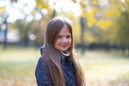 Autumn portrait of cute little blond girl in city park. Beautiful smiling child having fun outdoors...