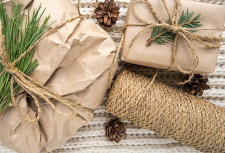 Preparing zero waste Christmas gift in craft paper on white table with fir branches, pine cones....