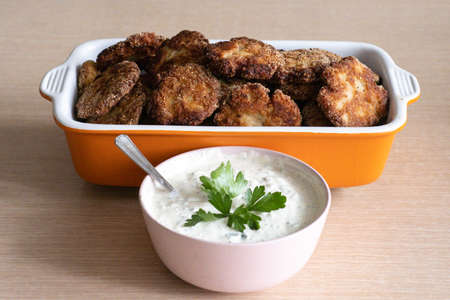 Dish with pork cutlets and white sauce studded with parsley on the table