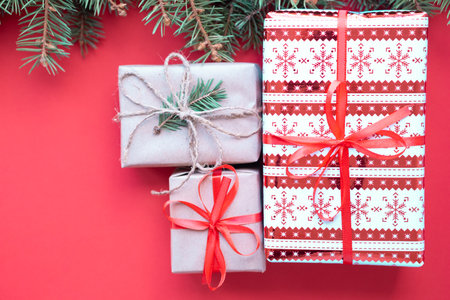Merry Christmas and Happy New Year gifts on red background with green fir branches. Christmas tree and present flatly. Flat lay, top view, copy space for textの写真素材