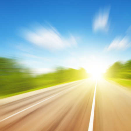Road in motion blur and blue sky with sun.の写真素材