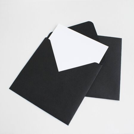 Two black envelopes with white paper on grey background. Postcard template.