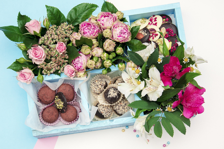 handmade chocolates decorated in a wooden box with beautiful fresh flowers bouquetの写真素材