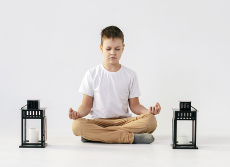 boy sitting in lotus position in yoga on whiteの写真素材