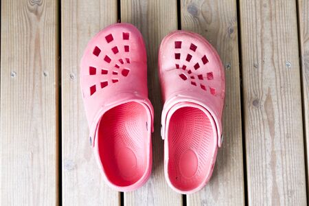 Red garden slippers on wooden floor