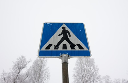 Pedestrian crossing road sign on winter sky backgroundの写真素材