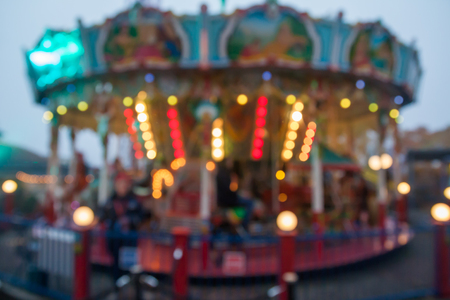 A blurry colorful carousel in the amusement park at evening illumination. The effect of bokeh.の写真素材