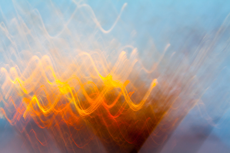 Abstract blurred light effect of orange waves on a blue background. Long exposure photo of moving camera.の写真素材