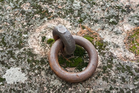 Closeup of a rusty old mooring loop fastened in a rock, used to tie up boats in the riverの写真素材