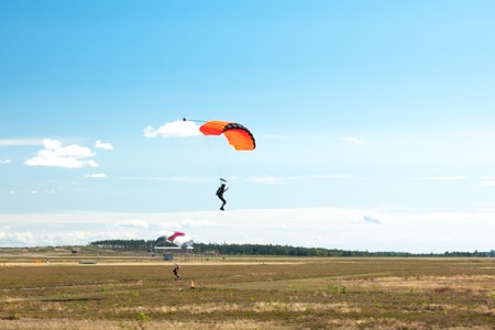 Two parachutists are landing on colorful parachutes to aerodrome.の写真素材