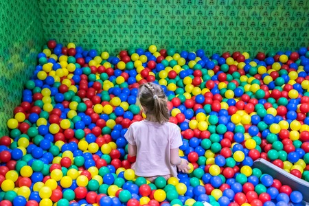 A girl in the pool with many colored balls in the kids playing room.の写真素材