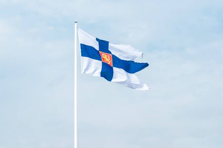 State flag of Finland with national coat of arms against blue skyの写真素材