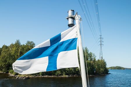 A finnish flag on a boat in the wind and high voltage line on lake Saimaa near the Lappeenranta, Finlandの写真素材