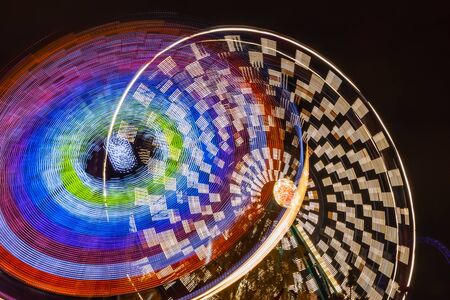Two rides in motion in amusement park, night illumination. Long exposure.の写真素材