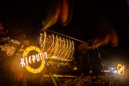 Helsinki, Finland - 19 October 2019: The Carnival of Light at the Linnanmaki amusement park. Rides Kieputin and chain carousel Ketjukaruselli in motion. Night illumination, long exposure.のeditorial素材