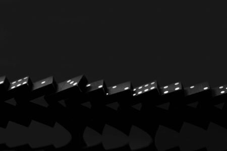 Black vintage falling dominoes on a black background, selective focus. WB photo.の写真素材