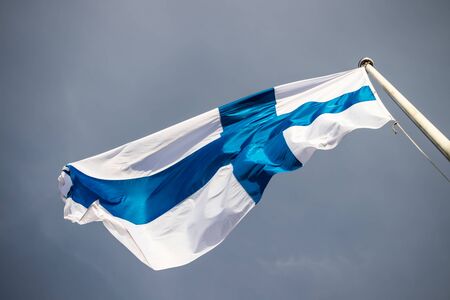 Finnish national flag on the wind against the blue skyの写真素材