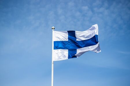 Finnish national flag on the wind against the blue skyの写真素材