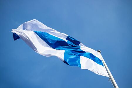 Finnish national flag on the wind against the blue skyの写真素材