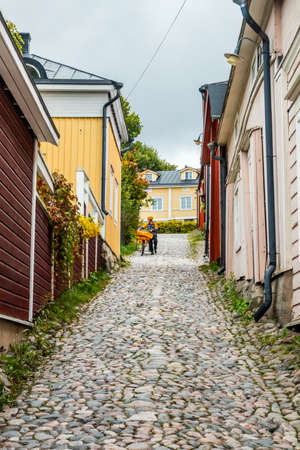 Porvoo, Finland - 2 October 2019: Postman on narrow street of Old Porvoo, Finland. Beautiful city autumn landscape with colorful wooden buildings.のeditorial素材